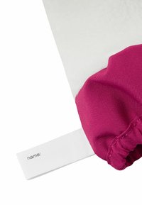 Lila Stoff mit gerafftem Rand, der ein weißes Etikett mit dem Text "Name:" zeigt. Glatte Oberfläche mit sichtbarer Nahtdetail.