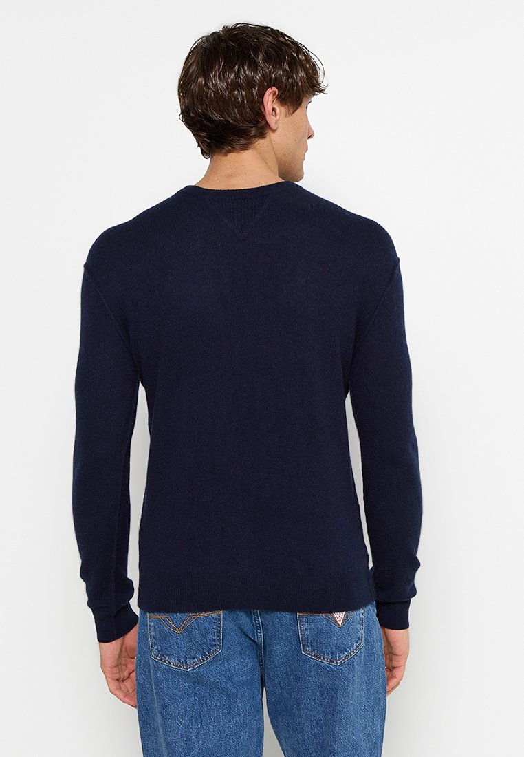Granatowy sweter z dekoltem w serek, długimi rękawami, ściągaczami na mankietach i u dołu, wykonany z miękkiego dzianiny. Wyświetlony widok z tyłu.