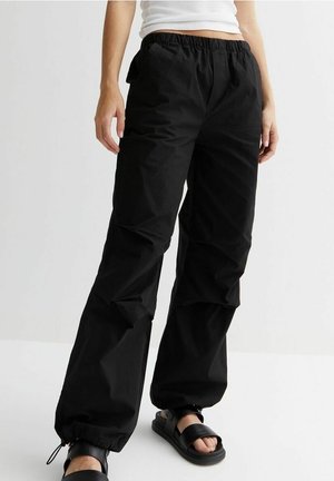 Black, loose-fitting trousers made of lightweight fabric, featuring an elastic waistband and gathered cuffs. Suitable for casual wear.