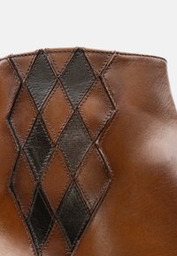 Braune Lederstiefel mit einem strukturierten Rautenmuster in Schwarz. Glatte Oberfläche mit dekorativer Naht entlang der Kanten.