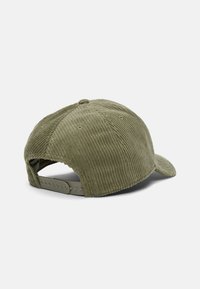 Gorra de pana verde oliva con textura acanalada, visera curva, correa de plástico ajustable en la parte trasera y detalle de costura circular en la parte superior.
