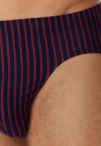 Marineblaue Shorts mit vertikalen roten Streifen, hergestellt aus weichem Baumwollstoff. Verfügt über einen bequemen elastischen Bund und einen taillierten Schnitt.