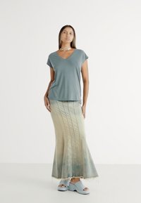 Pilkos v-neck marškinėliai, ilga gradientinė sijonas žaliai-mėlynas, flared forma, vertikalios siūlės, minkšta tekstūra, derinama su šviesiai mėlynomis klumpėmis.