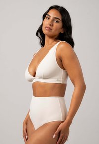 Cremefarbenes Lingerie-Set mit einem V-Ausschnitt-Bralette mit breiten Trägern und hochgeschnittenen Slips. Sanfte, glatte Textur mit minimalen Details.