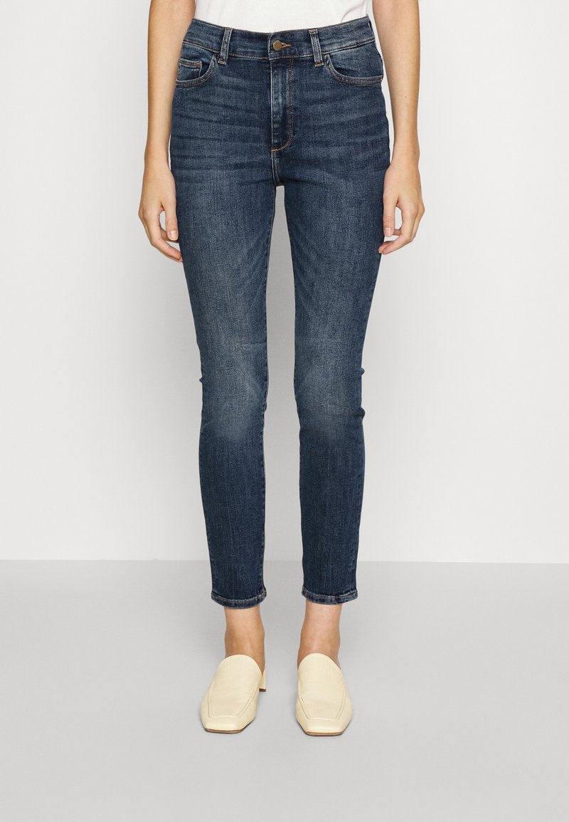 Mörkblå skinny jeans med hög midja, med framfickor, knappstängning och lätt blekning vid knäna.