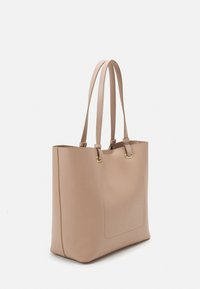 Beige tote bag made of smooth material, featuring two long straps, gold-tone hardware, and a front pocket with subtle stitching detail.