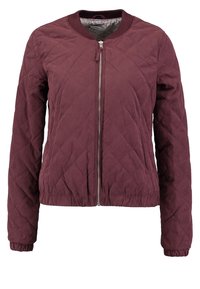 Giacca bomber trapuntata bordeaux con colletto e polsini a costine. Presenta una cerniera frontale completa e una vita elastica. Texture liscia.