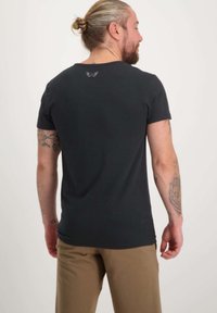 Musta puuvillapaita lyhyillä hihoilla ja pyöreällä kauluksella. Takakauluksessa pieni logo. Sileä pinta, normaali istuvuus.