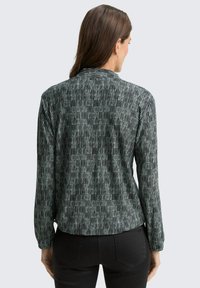 Black and white striped long-sleeve shirt with a soft texture and relaxed fit. Features a collar and rounded hemline.