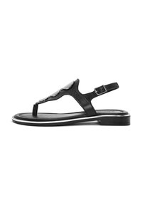 Sandal in pelle nera con puntale, cinturino alla caviglia regolabile, accentature metalliche, texture liscia e suola piatta con bordatura bianca.