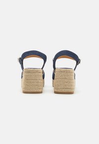 Námořnické tkaninové wedge sandály s propletenou jute platformou, kotníkovými popruhy a hnědou podšívkou. Design čtvercového podpatku s texturovaným povrchem.