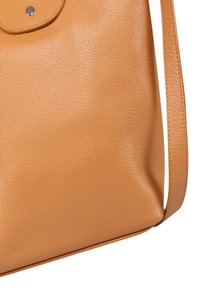 Bruine leren handtas met een gestructureerde afwerking, verstelbare schouderriem en een beveiligde ronde klep met metalen druksluiting.