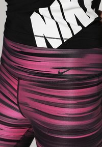 Leggings a fantasia rosa e nera con una texture liscia, dotati di una vita nera e di un piccolo logo Nike nero.