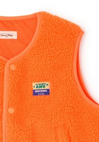 Heleoranž värvi pehme vest snap-nööpidega ja rinnal ristkülikukujuline plaastriga, millel on kiri "LA MAISON AMV SUPER VINTAGE".