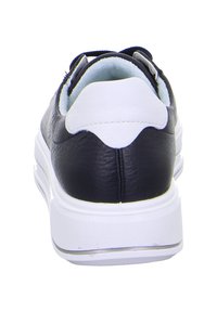 Schwarze und weiße Ledersneaker von hinten gesehen, die gepolsterten Kragen und eine dicke, weiße Sohle mit strukturiertem Grip zeigen.