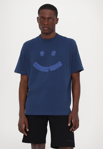 T-shirt en coton bleu marine avec un col rond, des manches courtes et un graphique de visage souriant en bleu clair, associé à un short noir.
