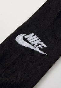 Μαύρες κάλτσες Nike με ένα χαρακτηριστικό άσπρο λογότυπο, κατασκευασμένες από μαλακό, πλεκτό υλικό με απαλή υφή και κλασικό σχήμα.