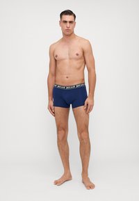 Boxeri scurti de culoare bleumarin, dintr-un material elastic, cu un brâu negru pe care este inscripționată în litere albe logo-ul "justcavalli".