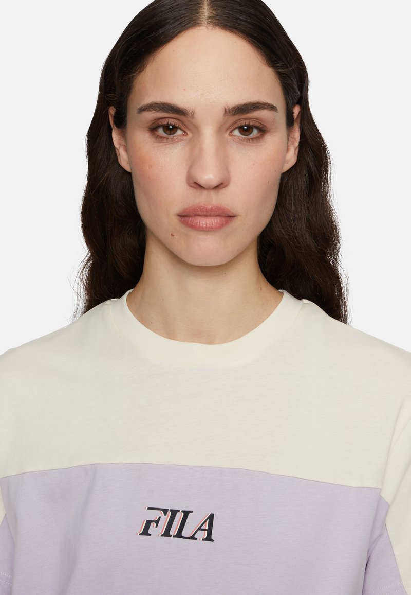 T-shirt en coton bicolore avec une partie supérieure jaune pâle, une partie inférieure violette claire et un logo FILA noir sur le devant.