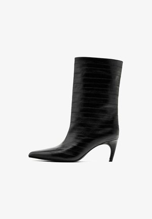 Černé kotníkové boty vyrobené z texturované kůže, s špičatou špičkou a úzkým kuželovitým podpatkem. Vertikální pruhy dodávají detail.