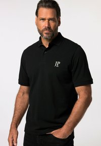 Sort polo-shirt med en tre-knaps lukning, korte ærmer og et hvidt JP 1880-logo på brystet. Blødt stof.