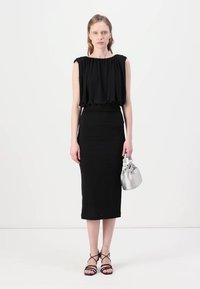 Black dress with a pleated top and fitted skirt. Matched with a silver handbag and strappy black sandals. Smooth texture, simple design.