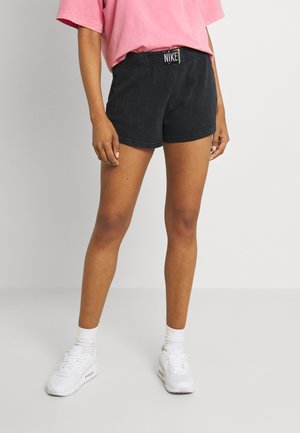 Black athletic shorts with an elastic waistband and Nike logo, made of soft fabric, paired with white sneakers and visible ankle socks.