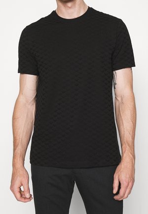 T-shirt noir texturé à manches courtes avec un motif en relief. Encolure ronde avec une finition douce et lisse, silhouette ajustée.