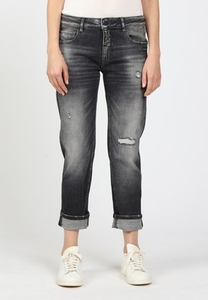 Graue Jeans aus Denim mit einem abgenutzten Finish, ausgestattet mit Rissen und hochgekrempelten Säumen, kombiniert mit weißen Turnschuhen. Klassisches Fünf-Taschen-Design.