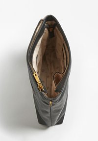 Czarna skórzana torebka na ramię z zamknięciem na suwak, teksturowanym wnętrzem i beżowym podszewką z powtarzającym się wzorem logo. W komplecie kieszonki wewnętrzne.