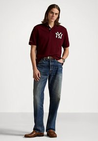 Μπορντό πόλο πουκάμισο με λογότυπο NY, συνδυασμένο με ξεβαμμένο μπλε τζιν. Καφέ δερμάτινα παπούτσια ολοκληρώνουν την εμφάνιση. Απλός, κομψός σχεδιασμός.