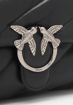 Sac à bandoulière en cuir matelassé noir avec une bandoulière chaîne argentée et une fermeture argentée ornée de deux oiseaux se faisant face.