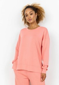 Felpa rosa oversize con collo rotondo, maniche lunghe e orlo a costine. Tessuto morbido con una vestibilità ampia, abbinata a pantaloni coordinati.