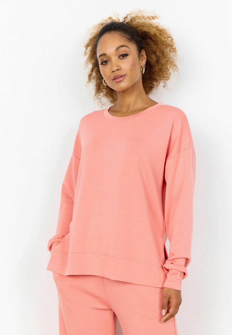 Felpa rosa oversize con collo rotondo, maniche lunghe e orlo a costine. Tessuto morbido con una vestibilità ampia, abbinata a pantaloni coordinati.