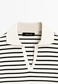 Haut en maille côtelée blanche avec des rayures horizontales noires, un col blanc et un décolleté en V avec une étiquette noire "Massimo Dutti" à l'intérieur.