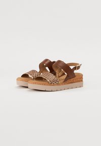 Brown leather and woven strap sandals with a cork footbed, featuring a medium-height wedge and a light-colored rubber sole.