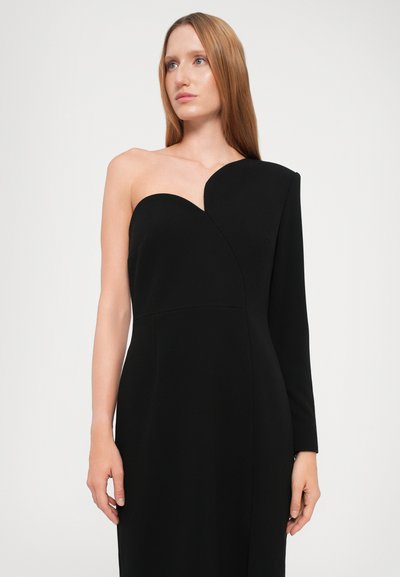 Crna haljina s jednim ramenom s tijesnim korzetom. Glatka, mat tkanina sadrži dekolte u obliku srca i dugu rukavu s jedne strane.