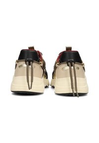 Baskets beige et noires avec une finition texturée, dotées de lacets rayés, d'accents métalliques et d'une semelle épaisse et rembourrée.