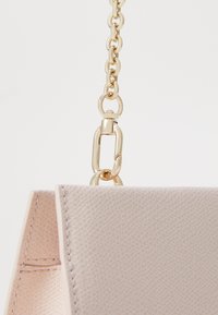 Borsa in pelle texturizzata rosa con tracolla in catena dorata. Presenta un design strutturato e cuciture visibili lungo i bordi.