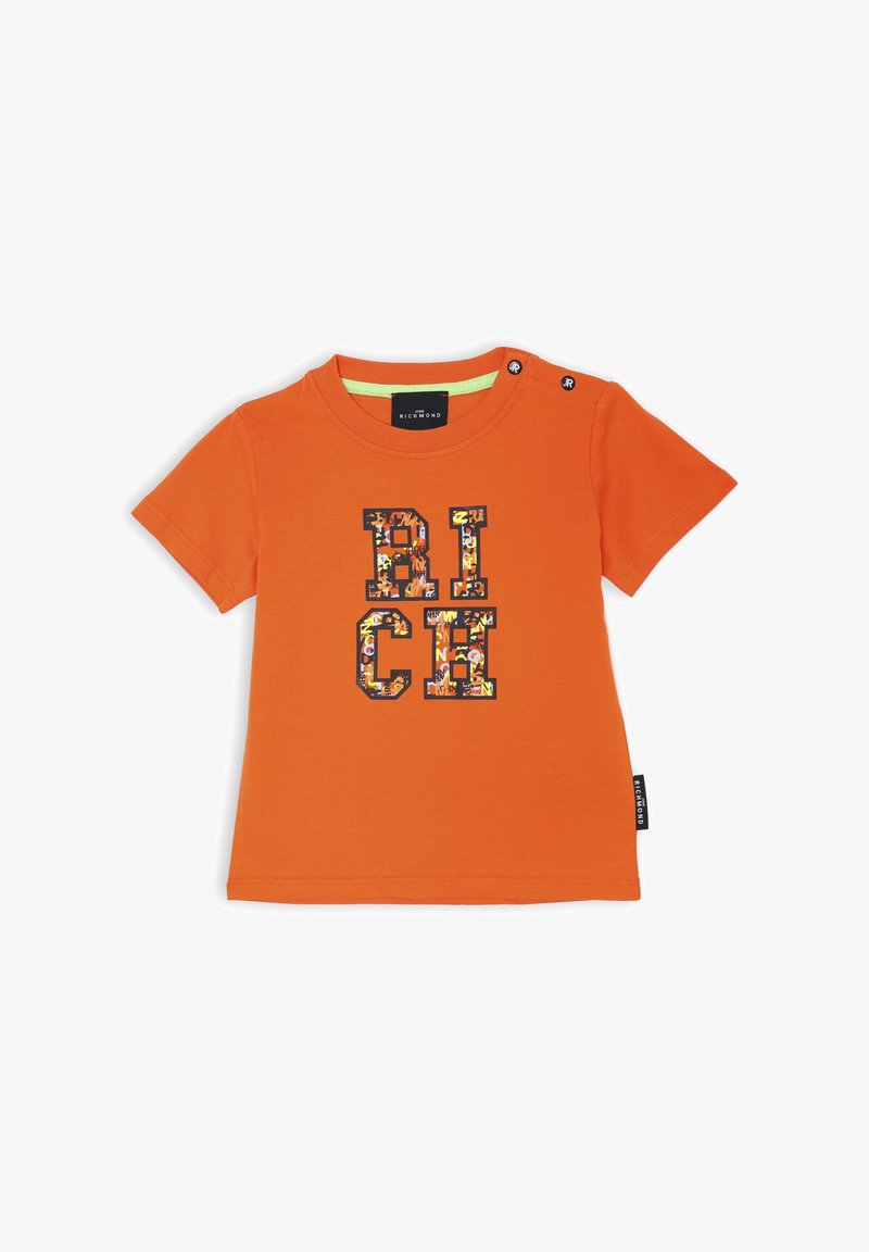 T-shirt arancione a maniche corte in cotone, con una stampa grafica che riporta la scritta "RICH" in lettere multicolori e bottoni a pressione sulla spalla.
