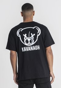 Černé bavlněné tričko s bílou grafikou medvědí tváře s očima ve tvaru X a textem "KAVANAGH" pod ním, volný střih.