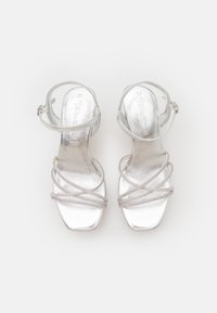 Silver high-heeled sandals with multiple crossed straps, metallic finish, an ankle strap, and a square toe design. Size 37 marked inside.