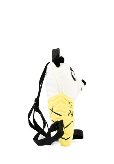 Sac à dos en peluche en forme de tête de panda posé sur une banane jaune, avec des sangles noires et une fermeture éclair, sur fond blanc.