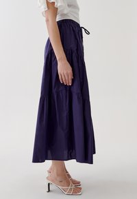 Gonna maxi blu navy con design a strati, realizzata in tessuto leggero. Caratterizzata da una vita elasticizzata e un cordoncino per la regolazione.
