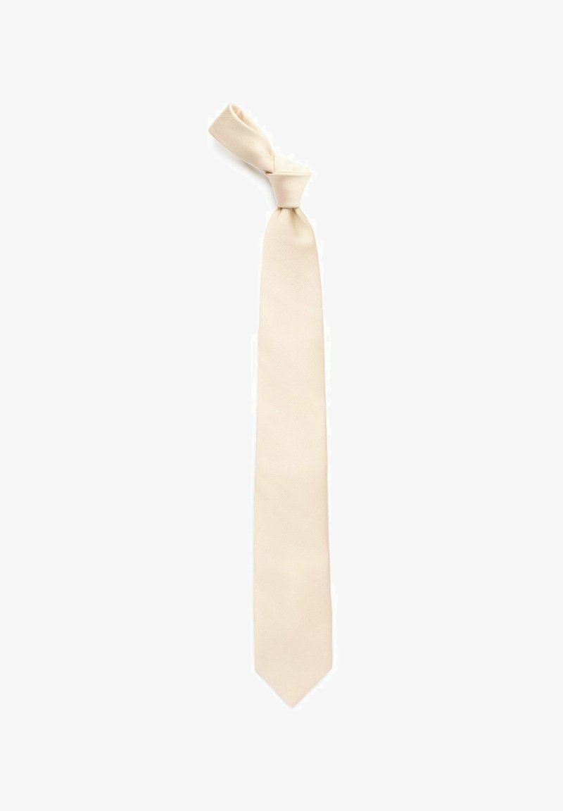 Beige slips med en strukturerad yta, med en knuten topp och en rak avsmalnande ände. Enkel design, lätt material.
