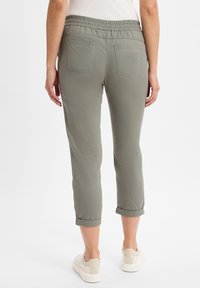 Hellgrüne, cropped Hose mit entspannter Passform, elastischem Bund und umgeschlagenen Säumen. Verfügt über zwei Gesäßtaschen und einen weichen, strukturierten Stoff.