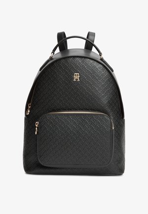 Svart ryggsekk i teksturert lær med frontlomme med glidelås, gullfarget logo og metallbeslag, håndtak på toppen og justerbare skulderstropper.