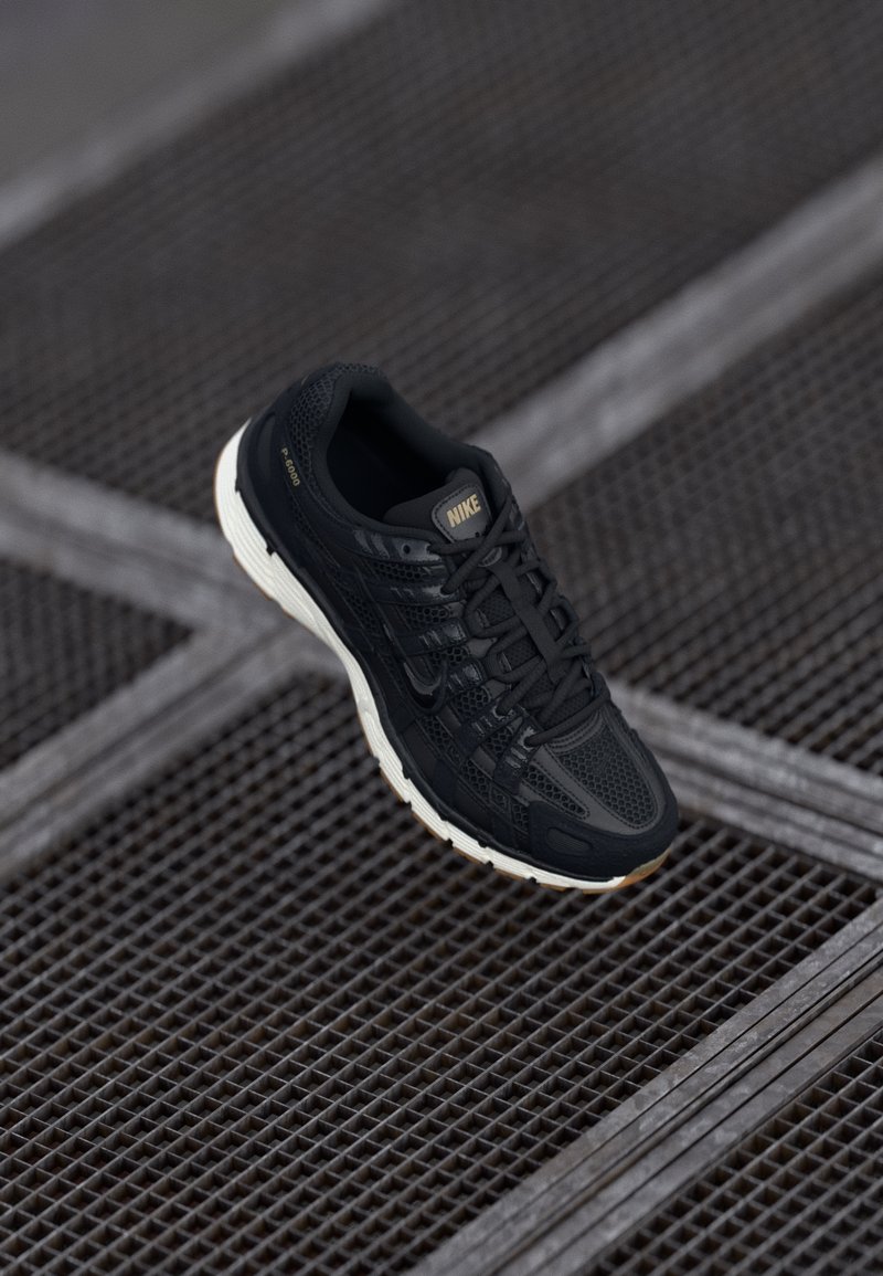 Černá běžecká obuv Nike s texturovaným síťovaným svrškem, gumovou podrážkou a jemnými zlatými akcenty. Obsahuje šněrování a polstrovanou podrážku.