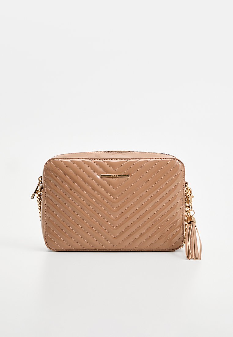 Sac à main matelassé beige avec un motif en chevron, quincaillerie dorée et un accent en frange. Fermeture à glissière et bandoulière en chaîne détachable.