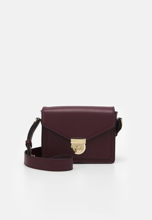 Burgundowa skórzana torebka na ramię z złotym okrągłym zapięciem, charakteryzująca się zarysowanym designem, regulowanym paskiem i minimalistycznymi akcentami.